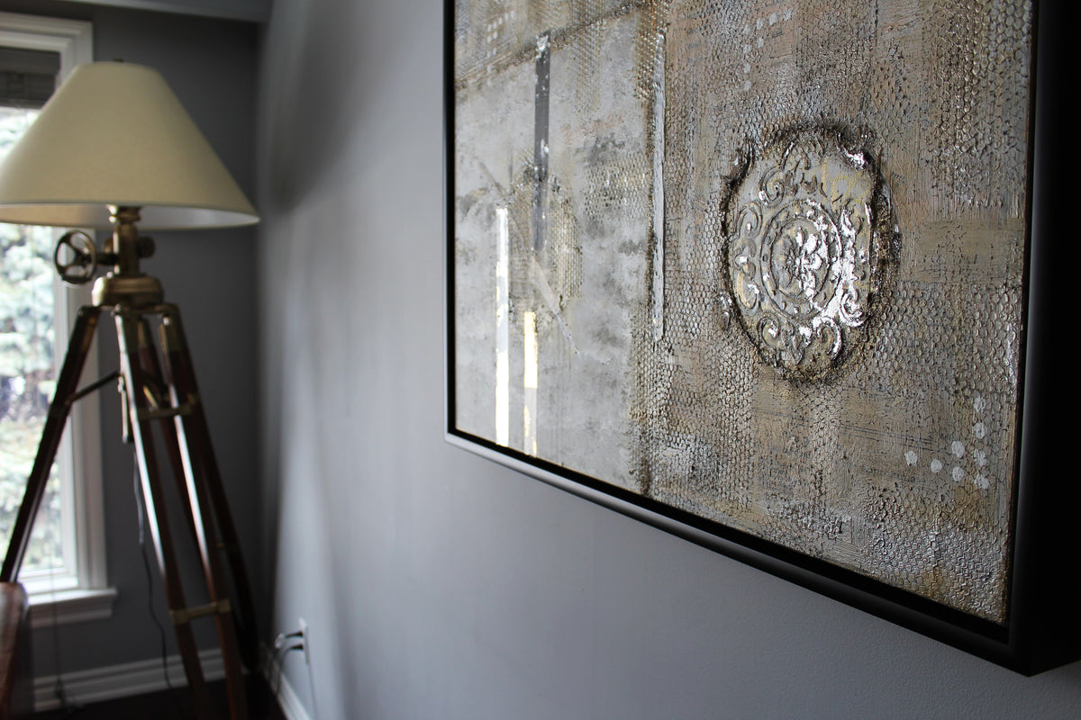 Pilgrimage original canvas in a black frame beside a floor lamp
